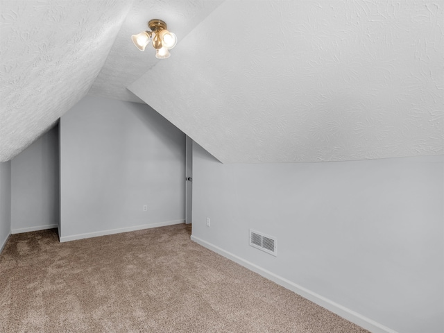 additional living space featuring carpet flooring, a textured ceiling, and vaulted ceiling