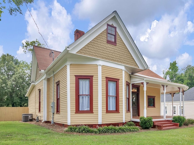 view of front facade featuring central AC unit, covered porch, and a front lawn