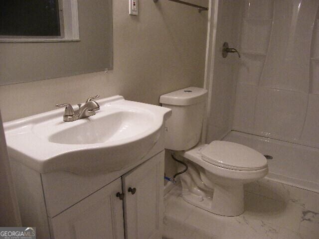 bathroom with vanity, toilet, and a shower