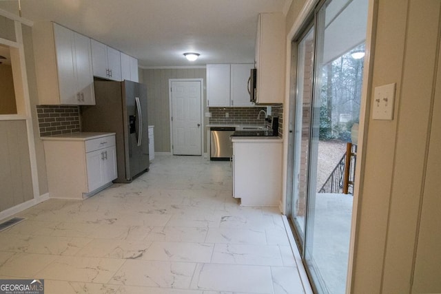 kitchen with stainless steel appliances, sink, white cabinets, and decorative backsplash