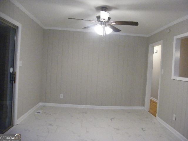 empty room with crown molding, ceiling fan, and wood walls