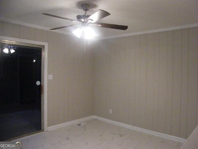 unfurnished room with crown molding, wooden walls, and ceiling fan