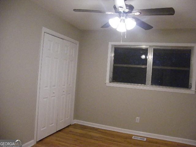 unfurnished bedroom featuring ceiling fan, hardwood / wood-style floors, and a closet