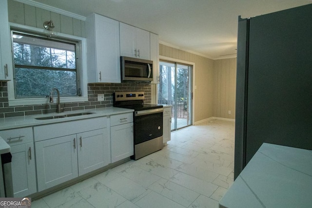 kitchen with sink, crown molding, appliances with stainless steel finishes, tasteful backsplash, and white cabinets