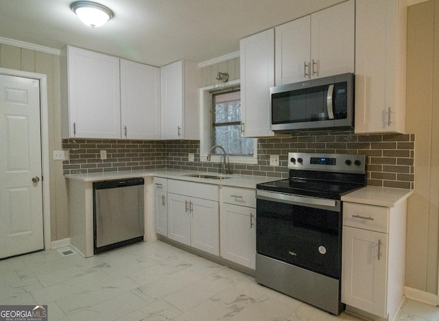 kitchen with appliances with stainless steel finishes, tasteful backsplash, sink, white cabinets, and ornamental molding