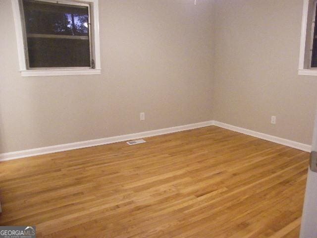 unfurnished room with hardwood / wood-style flooring