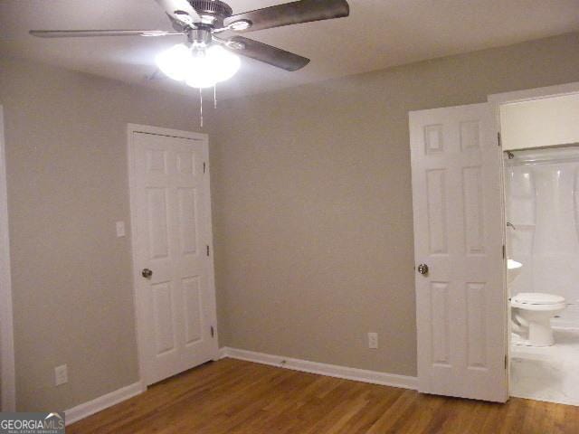 unfurnished bedroom with ensuite bathroom, hardwood / wood-style floors, and ceiling fan