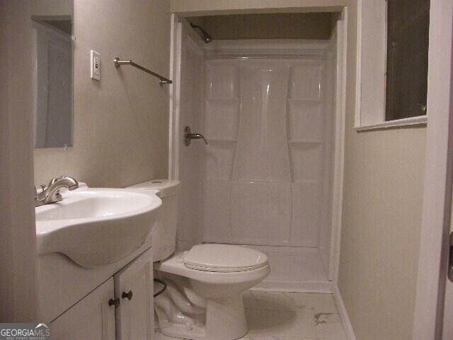 bathroom featuring a shower, vanity, and toilet