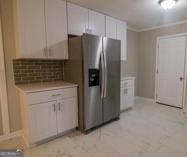 kitchen with white cabinetry, stainless steel fridge, crown molding, and backsplash