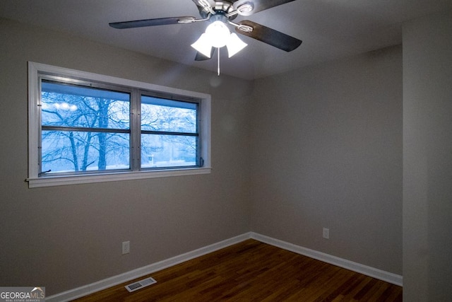 empty room with ceiling fan and dark hardwood / wood-style flooring