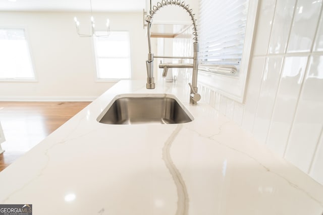 details with light stone countertops, hardwood / wood-style flooring, and sink