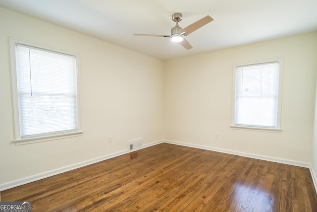 spare room featuring ceiling fan, a healthy amount of sunlight, and dark hardwood / wood-style floors