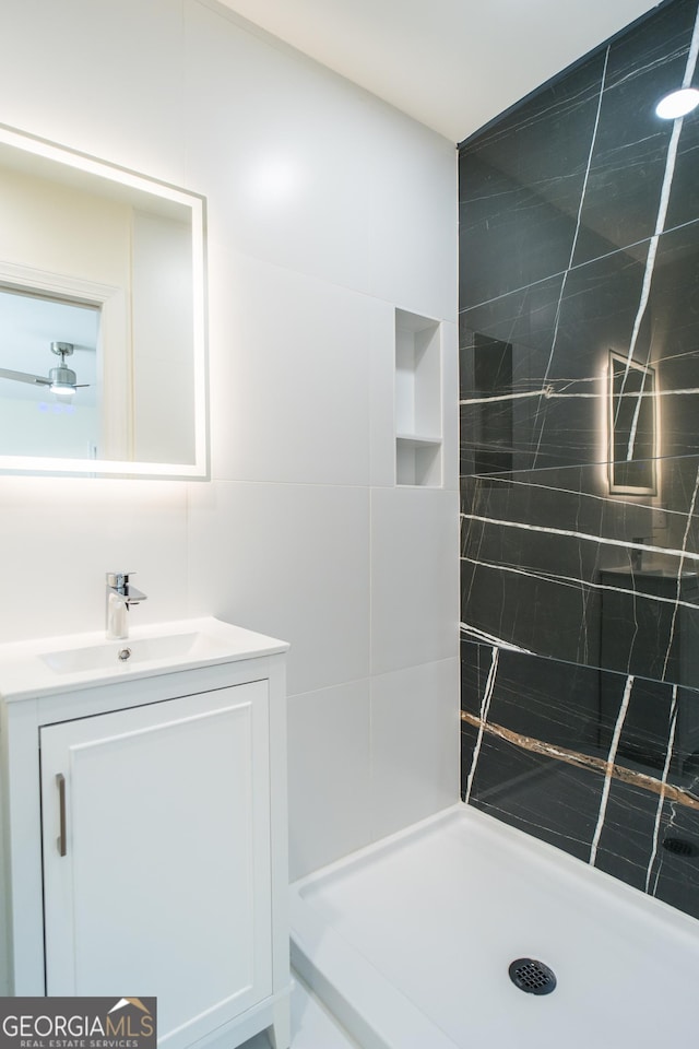 bathroom featuring vanity, tiled shower, and tile walls