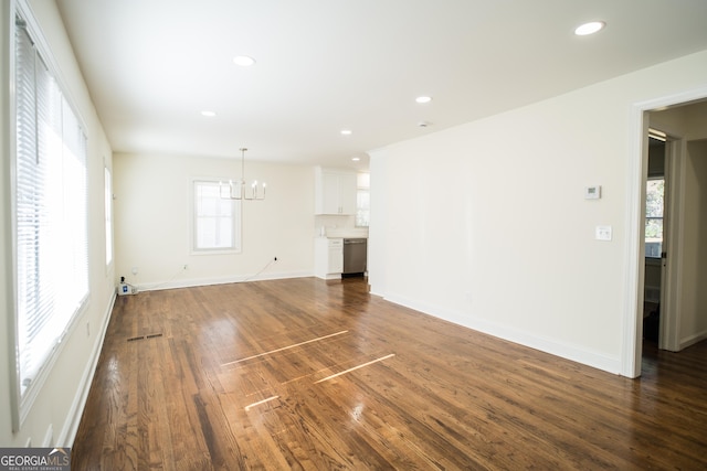 unfurnished living room with dark wood-type flooring and an inviting chandelier