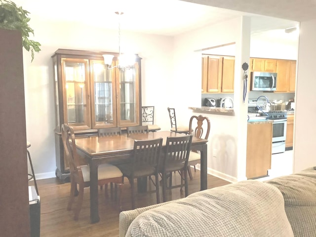 dining space with dark hardwood / wood-style flooring, a notable chandelier, and sink