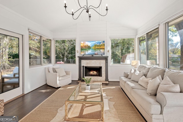 sunroom with a tile fireplace, lofted ceiling, and a notable chandelier