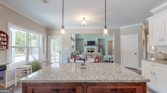 kitchen with white cabinetry, decorative light fixtures, and ornamental molding