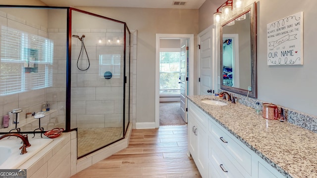 bathroom featuring vanity, wood-type flooring, and plus walk in shower