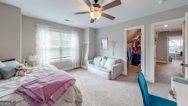 carpeted bedroom with ceiling fan, a spacious closet, and a closet