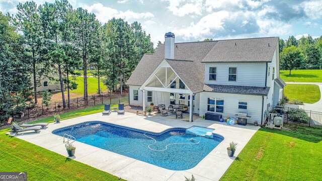 rear view of house featuring a fenced in pool, a yard, a patio, and an outdoor hangout area