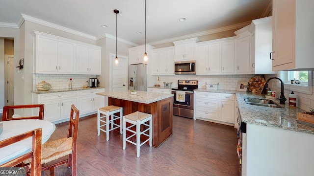 kitchen with appliances with stainless steel finishes, pendant lighting, a center island, dark hardwood / wood-style floors, and white cabinetry