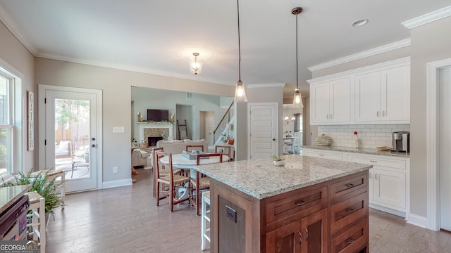 kitchen with pendant lighting, light wood-type flooring, white cabinetry, and a kitchen island