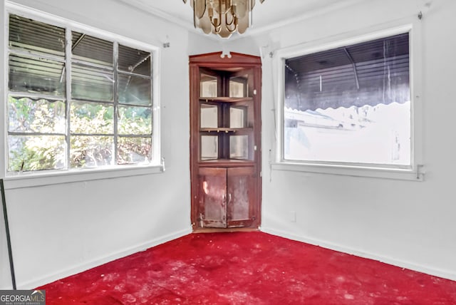 carpeted empty room with crown molding and a notable chandelier