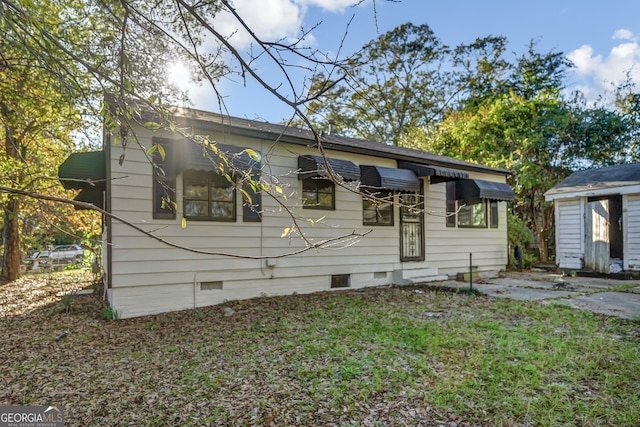 bungalow-style house featuring a storage unit