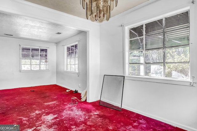 carpeted spare room with a textured ceiling and a notable chandelier