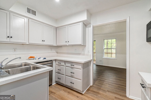 kitchen featuring sink, stainless steel dishwasher, white cabinets, and light hardwood / wood-style flooring