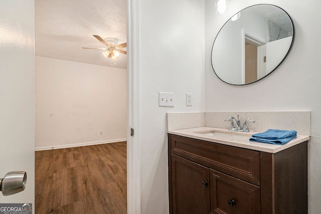 bathroom featuring vanity, wood-type flooring, a textured ceiling, and ceiling fan