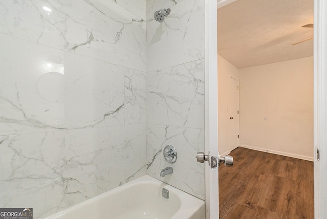 bathroom featuring tiled shower / bath combo, hardwood / wood-style floors, and a textured ceiling