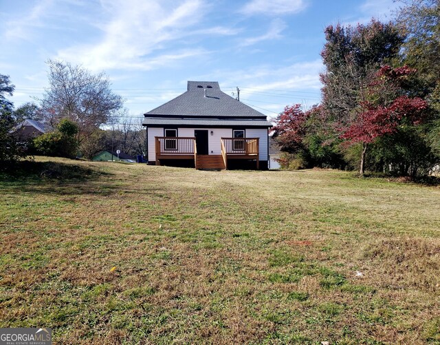 back of property with a wooden deck and a yard