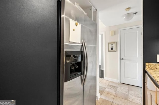 kitchen with light stone counters, baseboards, and stainless steel fridge