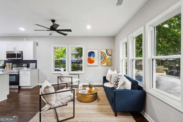 living room featuring ceiling fan and dark wood-type flooring