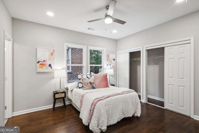 bedroom featuring ceiling fan, dark hardwood / wood-style floors, and two closets