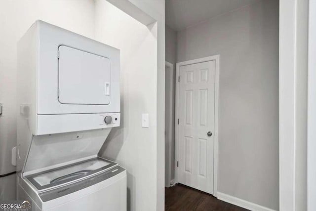 laundry room with stacked washing maching and dryer and dark hardwood / wood-style floors