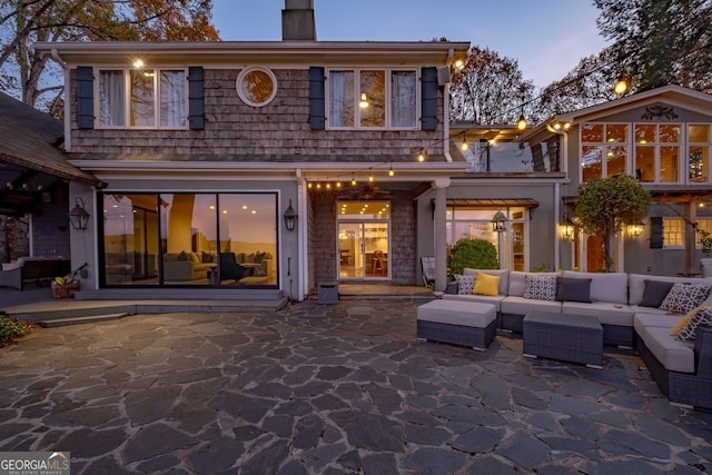 back house at dusk with a patio area and an outdoor hangout area