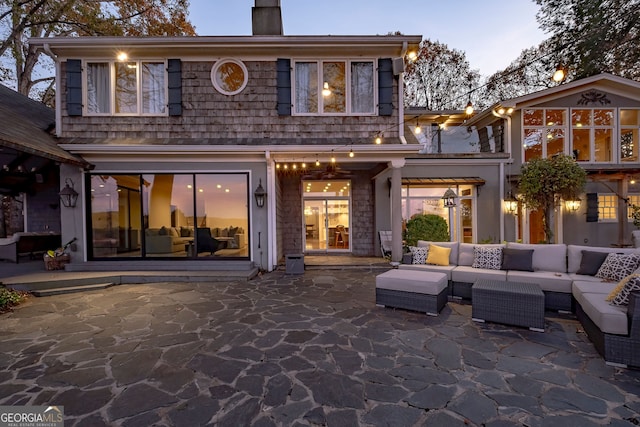 back house at dusk with a patio area and an outdoor living space