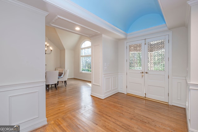 foyer with light hardwood / wood-style floors, an inviting chandelier, crown molding, and vaulted ceiling