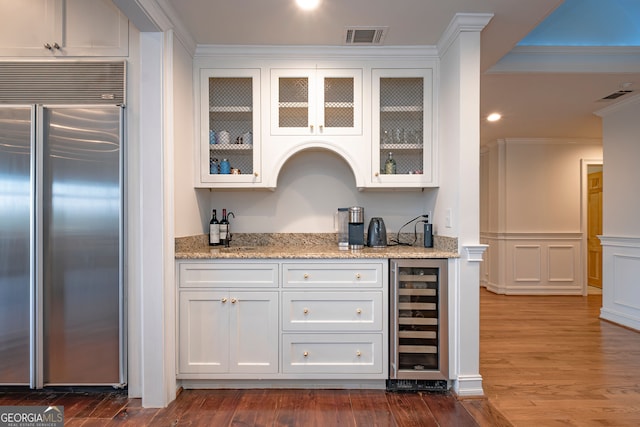 bar with white cabinetry, wine cooler, dark hardwood / wood-style floors, built in refrigerator, and ornamental molding