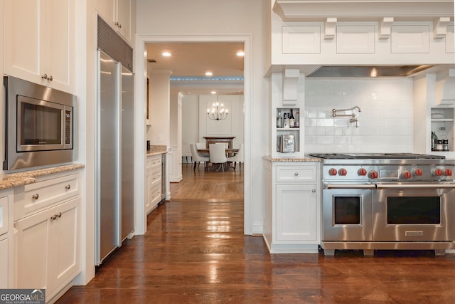 kitchen featuring dark hardwood / wood-style flooring, tasteful backsplash, light stone counters, built in appliances, and white cabinetry