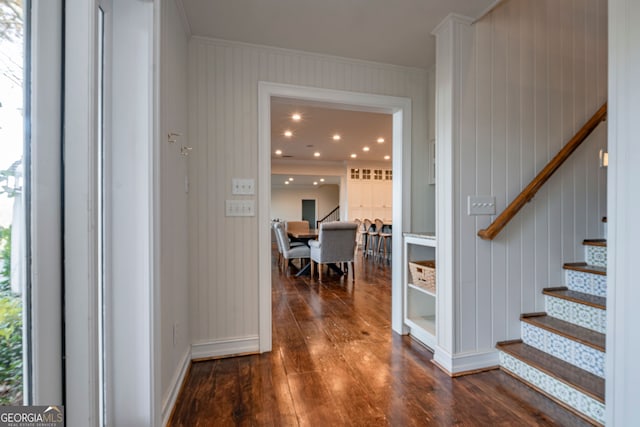 corridor featuring crown molding, dark hardwood / wood-style flooring, and wood walls