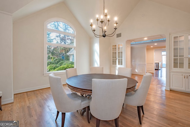 dining area with high vaulted ceiling, light hardwood / wood-style floors, and a notable chandelier