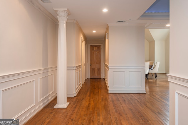 hallway with ornamental molding, decorative columns, and dark wood-type flooring