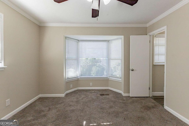 carpeted spare room with ceiling fan, a healthy amount of sunlight, and ornamental molding