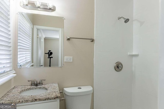 bathroom featuring a tile shower, vanity, and toilet