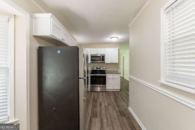 kitchen featuring appliances with stainless steel finishes, dark hardwood / wood-style flooring, ornamental molding, a textured ceiling, and white cabinets