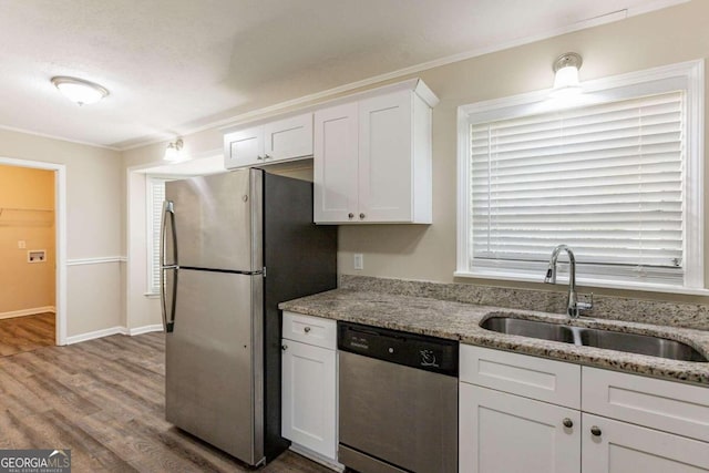 kitchen featuring sink, light stone countertops, appliances with stainless steel finishes, white cabinetry, and wood-type flooring