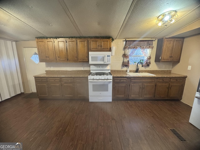 kitchen featuring a textured ceiling, white appliances, dark hardwood / wood-style floors, and sink